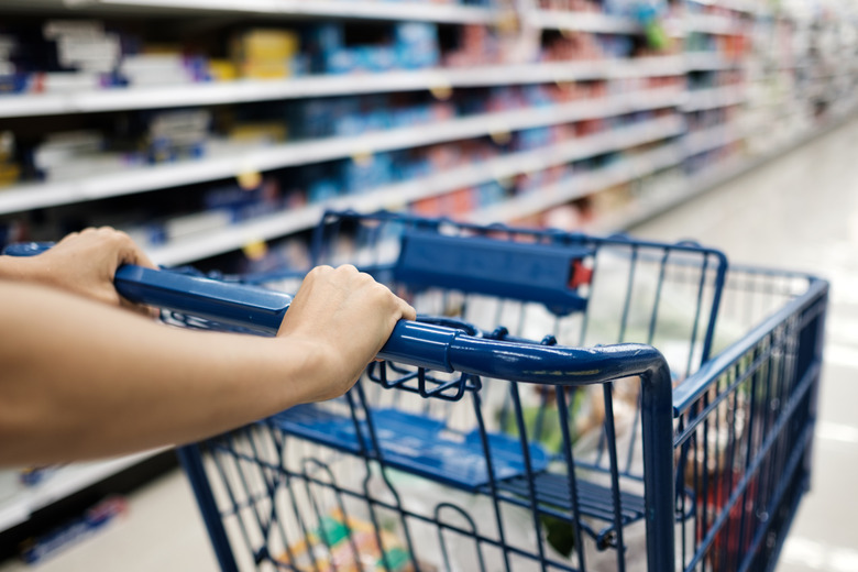 Closeup of shopper pushing a cart through a grocery aisle