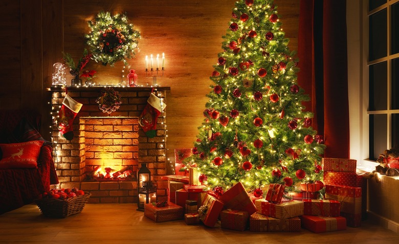 interior christmas. magic glowing tree, fireplace, gifts in dark