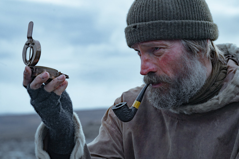 close up of a man with a beard looking at a compass