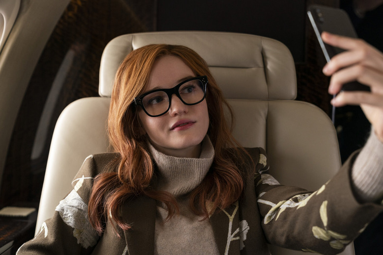 young woman wearing glasses and holding up smartphone