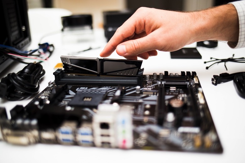 Hand assembling a desktop computer with a focus on the motherboard.