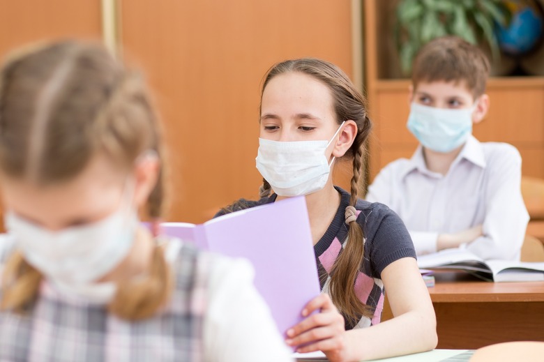 Pupils wearing protection mask to prevent virus during lesson in classroom