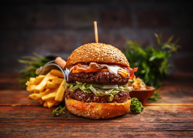 Fresh tasty burger and french fries on rustic wooden table.