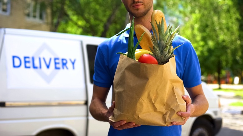 A delivery person carrying a grocery bag