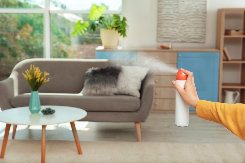 A person using an odor spray at home
