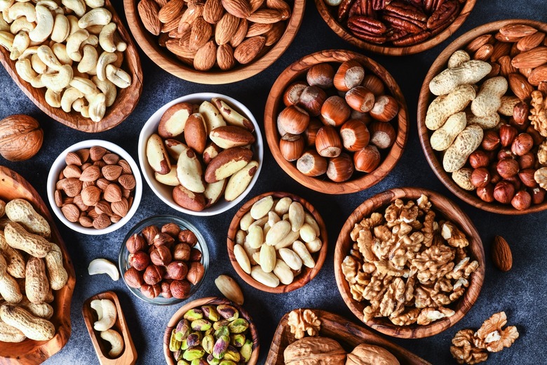 Mixed nuts in wooden bowls on black stone table