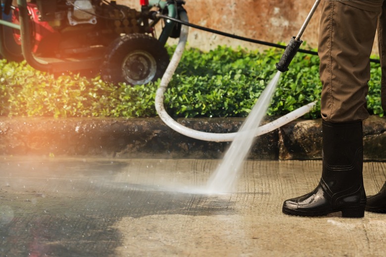 A person cleaning a driveway with a pressure washer.