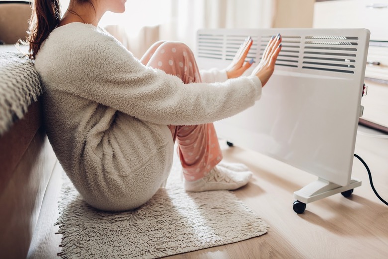 A woman using an electric heater at home