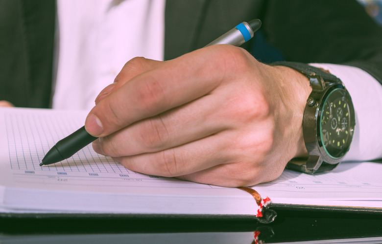Left handed businessman writing in notebook