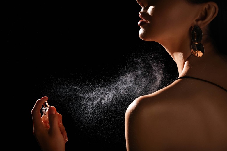 woman spraying perfume on body