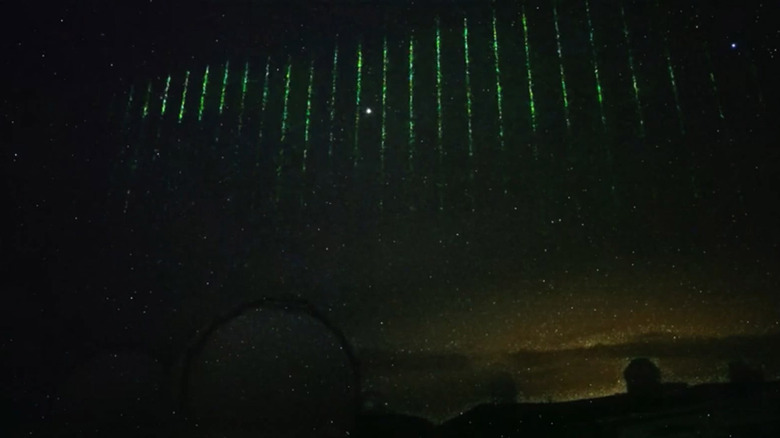 bright green lasers shooting down from sky