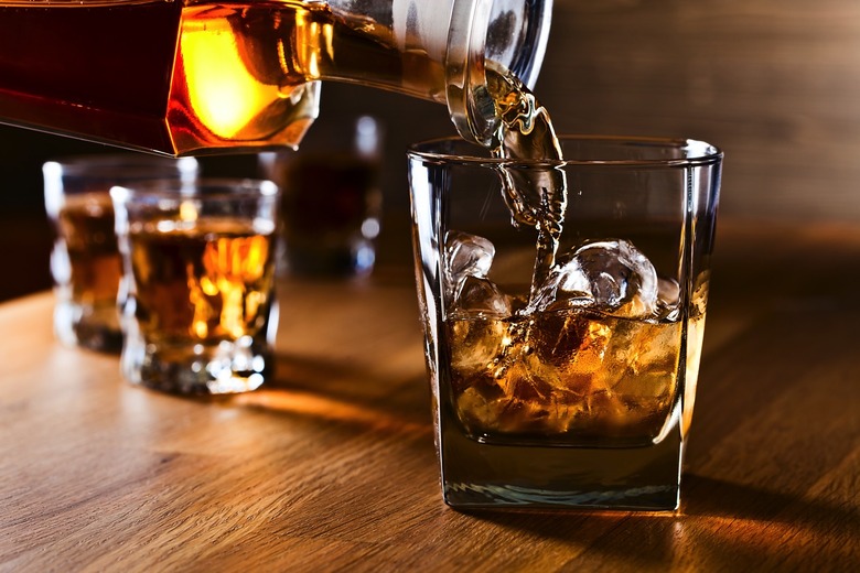 Whiskey and natural ice in a glass on old wooden table.